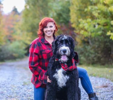 A photo of Krista Collier-Jarvis embracing a large black and white dog