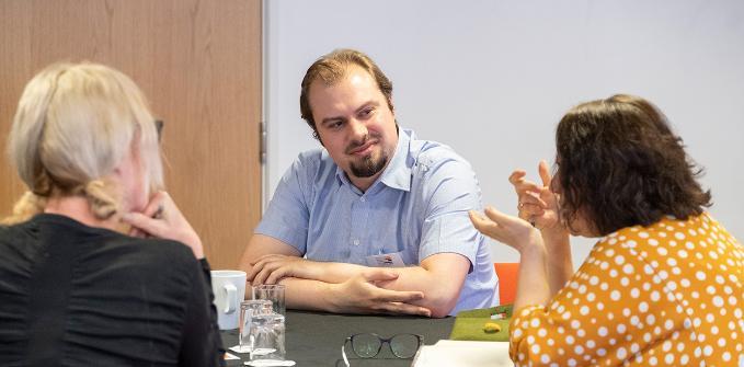 A group of 3 researchers gathered around a table having a discussion