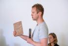 A person leading a training workshop. They are holding two books and are engaged in conversation.