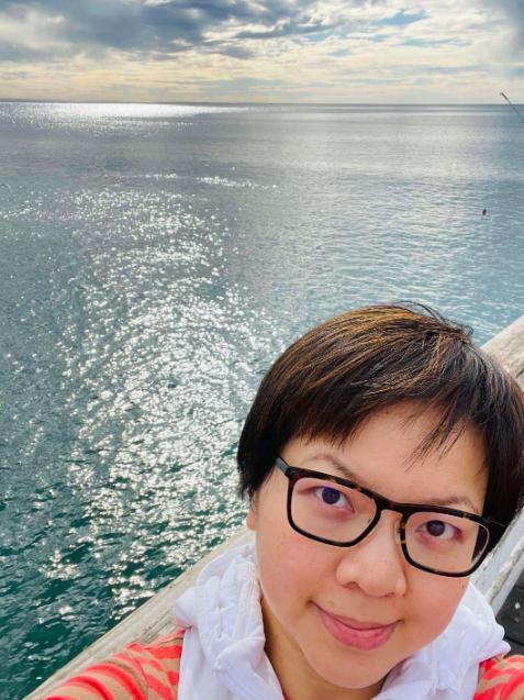 Student with glasses posing by the sea