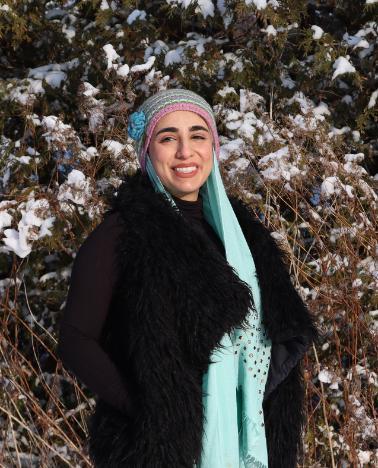 Student smiling by snowy bushes