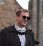 Student in sunglasses and white bow tie smiling