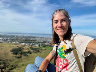 Student smiling with landscape of a grassy town in background