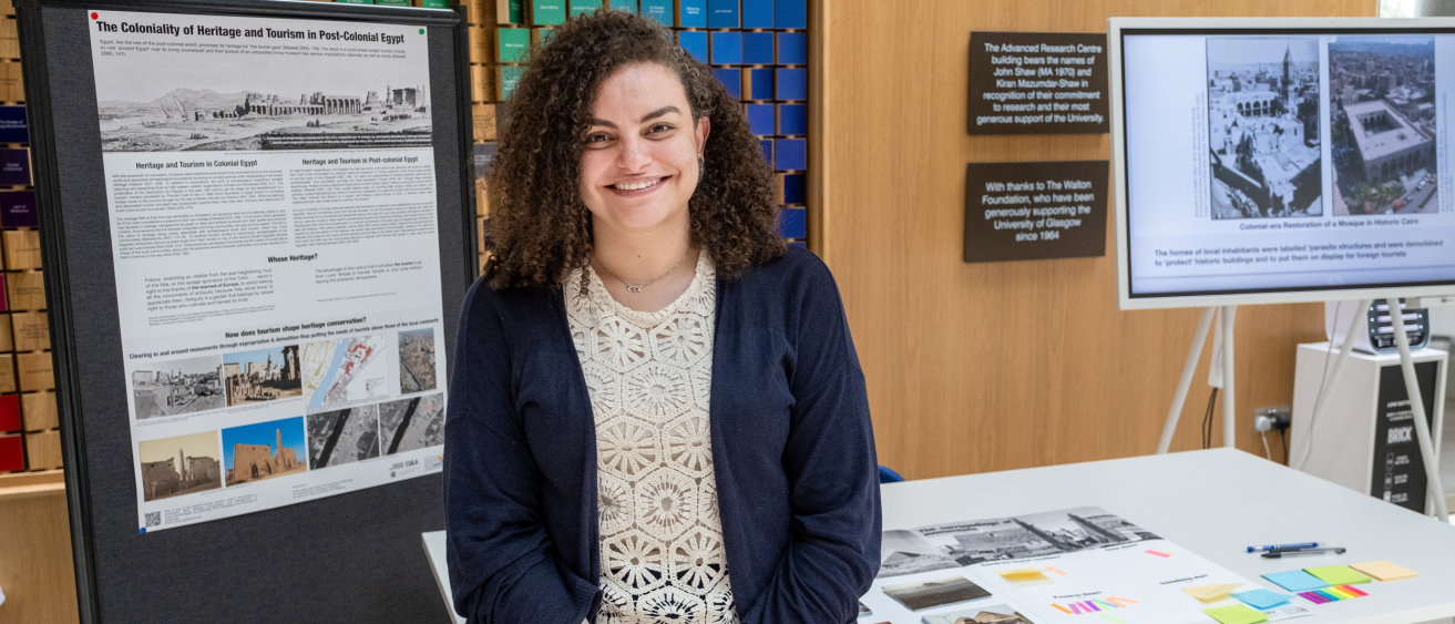 A doctoral student smiling in front of their research showcase exhibit