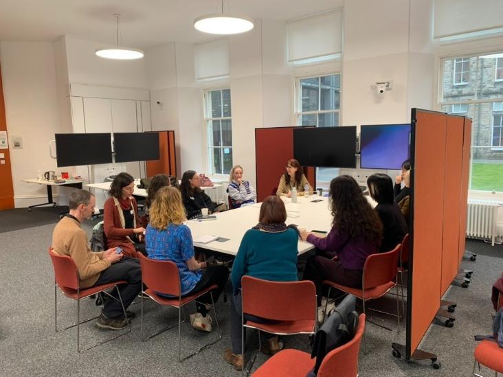 Participants seated around tables in a bright seminar room, engaged in a group discussion during a workshop.