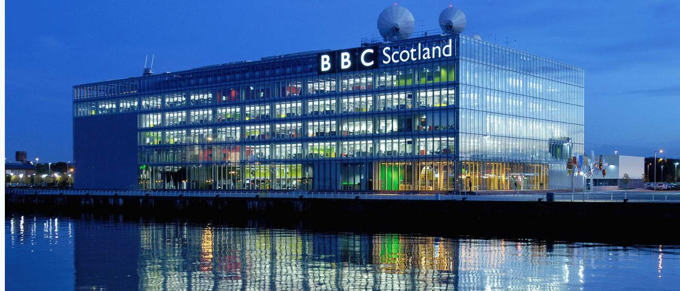 BBC Scotland headquarters beside the waterfront at dusk, reflected in the water below