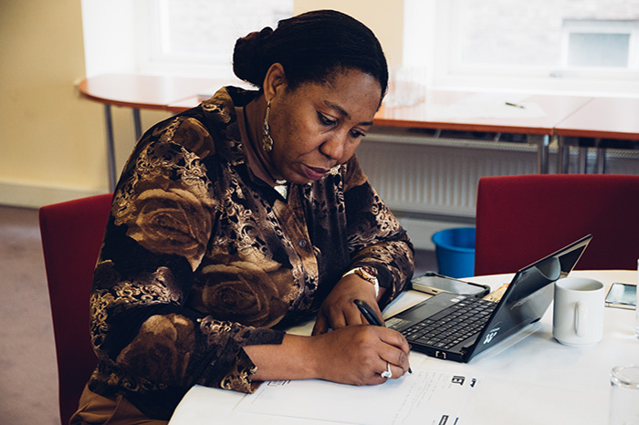Researcher takes notes next to a laptop at a SGSAH event