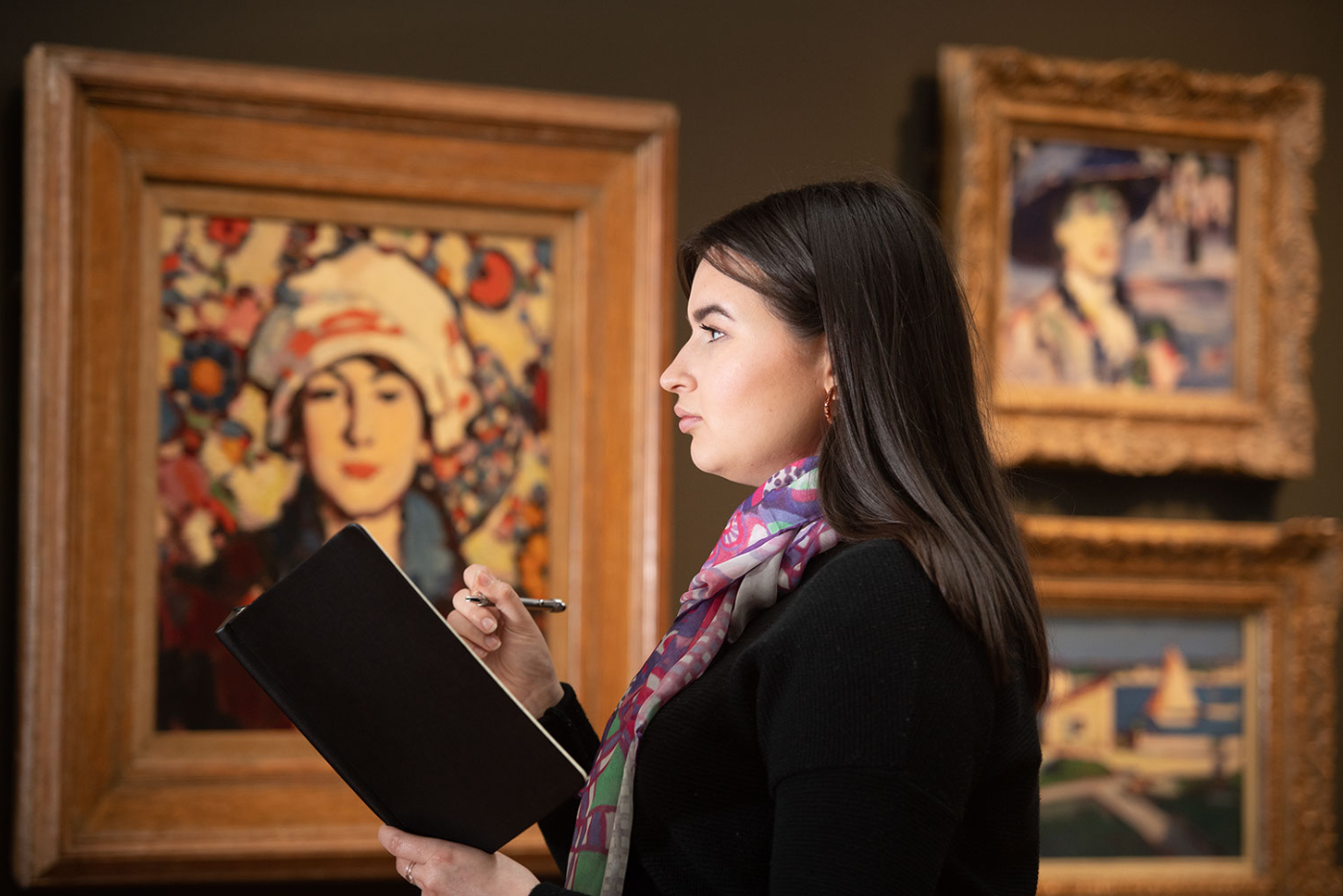 A student in a museum gallery studying a painting.