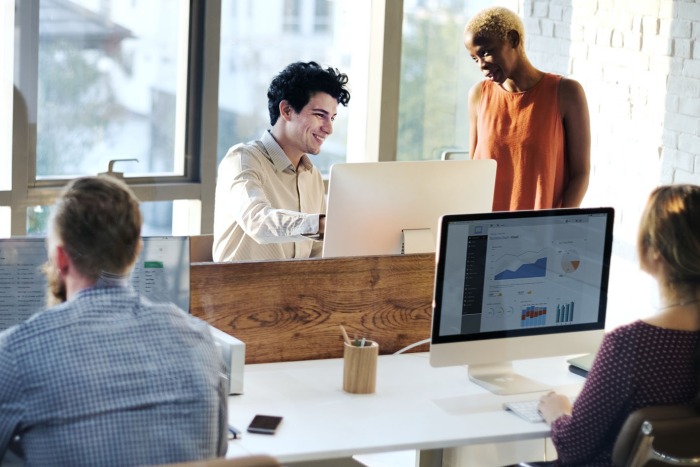 Four adults working together in a bright open plan office