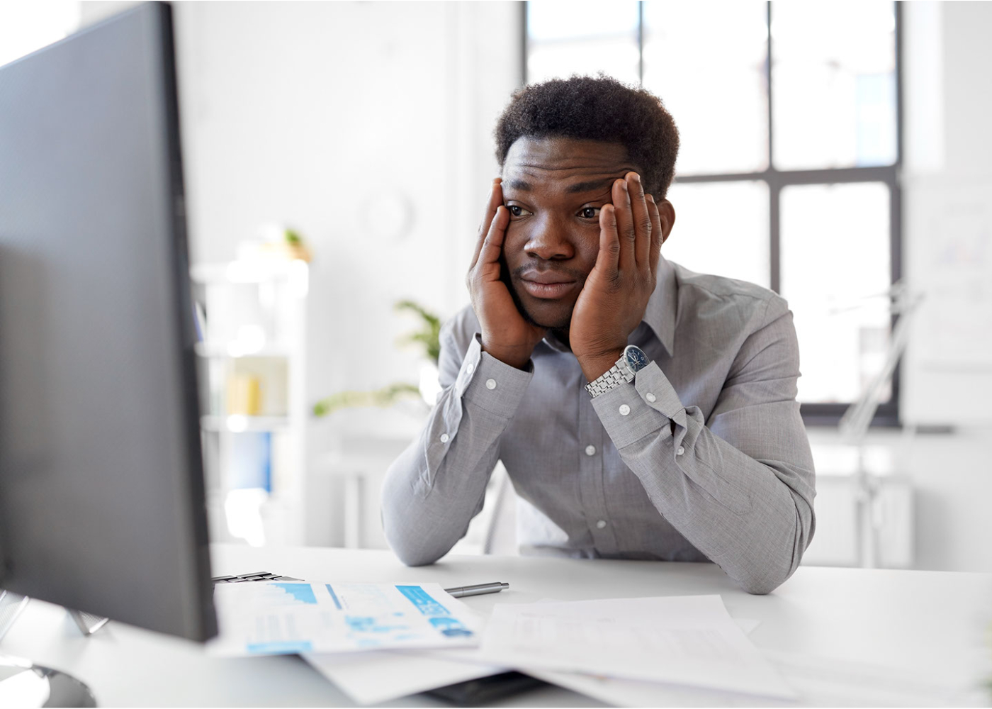 A man with an unhappy expression sitting in front of a computer